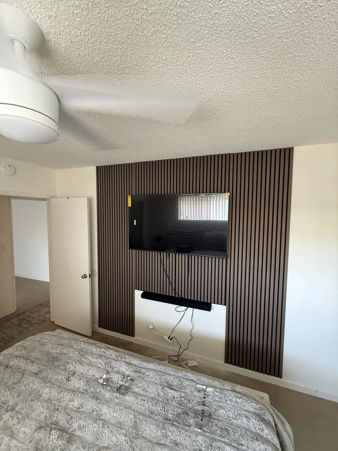 TV set against a vertical slat accent wall in a bedroom