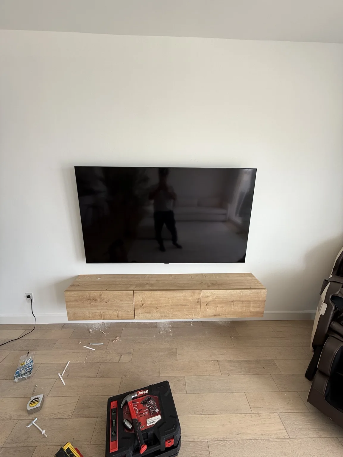 Wall mounted TV above a long oak tone floating entertainment console