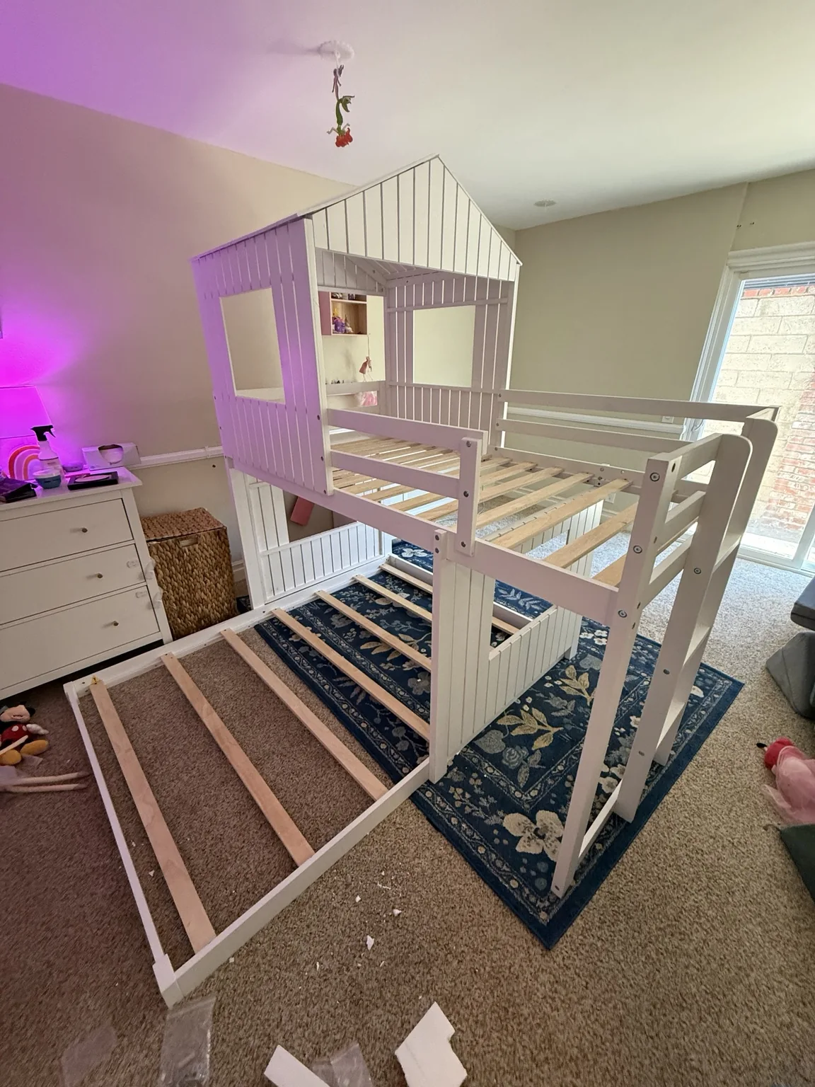 White two-level house-style bunk bed frame during assembly